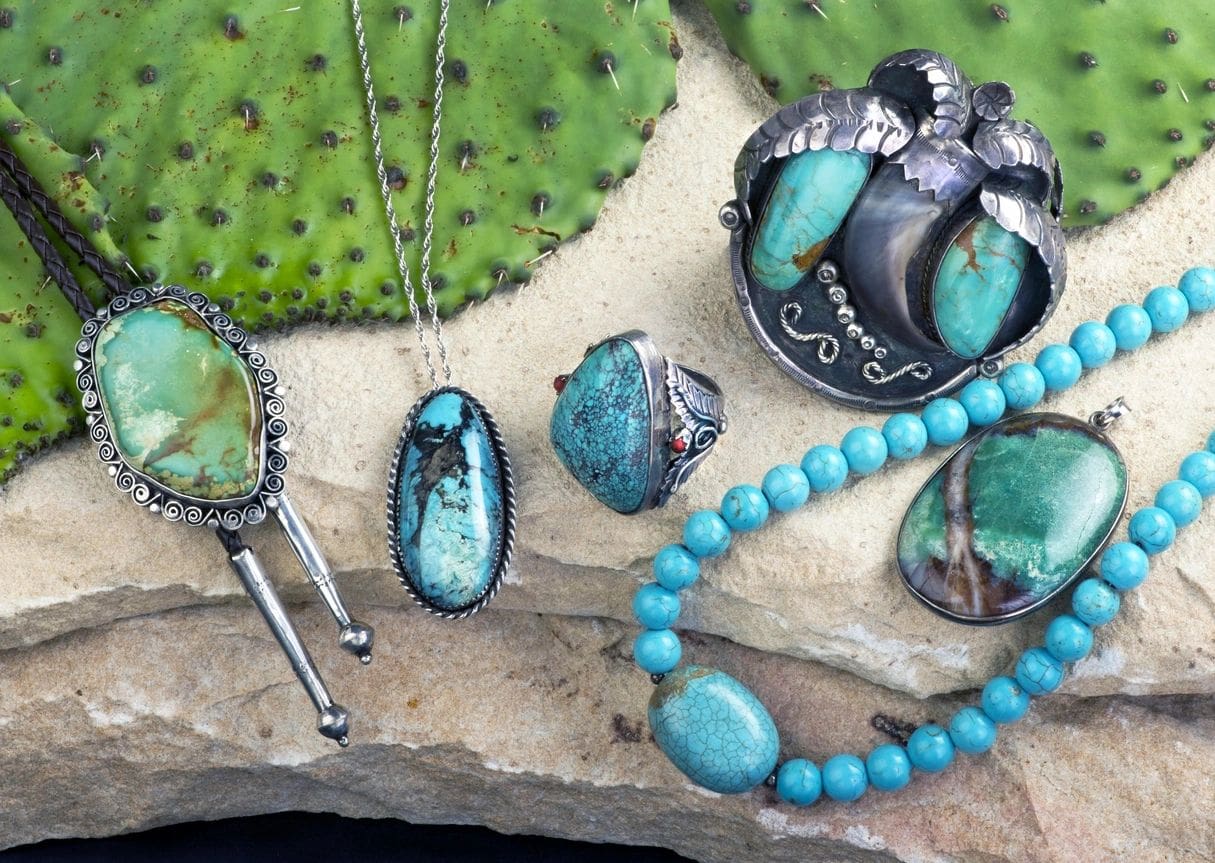 A collection of turquoise jewelry on a cactus.